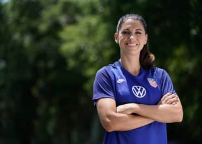 USWNT star forward Alex Morgan posing with arms crossed in her USWNT jersey