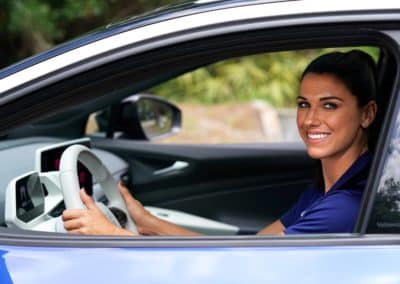 USWNT star forward Alex Morgan smiling as she drives the all-new Volkswagen ID.4 electric vehicle